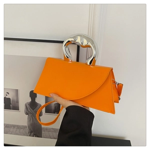 Detail of orange trapezoid handbag with sculptural silver liquid metal handle and matte finish