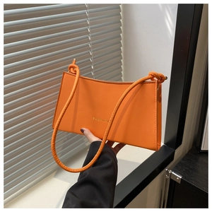 Détail du sac à bandoulière orange vif avec bandoulière à nœuds et lettrage doré