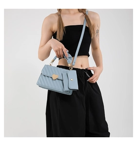 Detail view of light blue quilted bag with heart-shaped gold lock and ruched handle