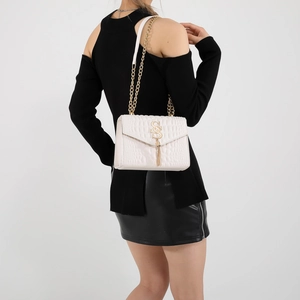 Sac matelassé blanc avec chaîne dorée et logo GS porté à l'épaule par un mannequin
