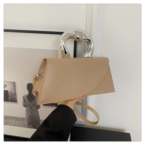 Detail of beige leather bag featuring a silver irregular metal handle and asymmetric flap