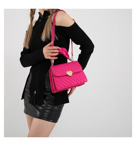 Detail of rose red quilted crossbody bag featuring a large gold heart clasp and top handle