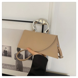 Detail of khaki leather handbag featuring a sculpted silver metal handle and wide strap