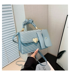 Detail of light blue crossbody bag with diamond quilting and heart-shaped gold clasp lock