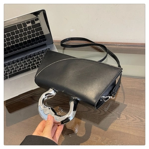 Detail view of a black crossbody bag with a unique silver circular metal handle