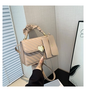 Detail of beige quilted handbag with golden heart lock and soft ruched handle
