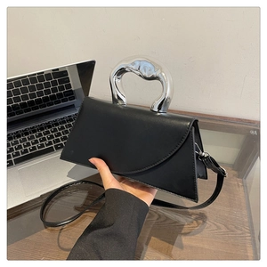 Detail of minimalist black leather handbag with unique silver sculptural metal handle