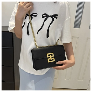 Close-up of black leather chain bag featuring a decorative gold rectangular metal clasp