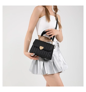Detail of black pleated PU handbag with golden heart-shaped clasp and dual straps
