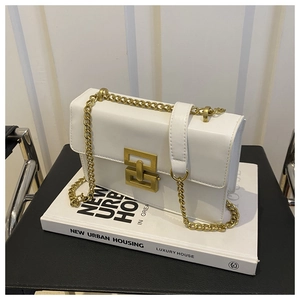 Detail of white rectangular crossbody bag featuring golden hardware and chain strap
