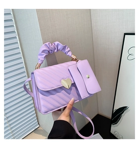 Detail of lavender quilted handbag with gold heart lock and ruffled cloud handle