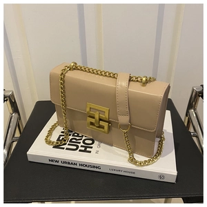 Detail of light beige crossbody bag with gold chain strap and geometric buckle clasp