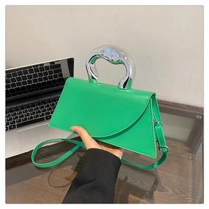 Detail of lime green crossbody bag featuring a unique silver sculptural metal handle