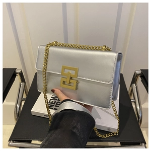 Detail of silver rectangular crossbody bag featuring a large gold interlocking buckle