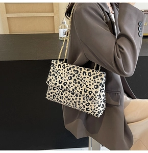 Detail of leopard print shoulder bag with gold chain strap worn with a blazer