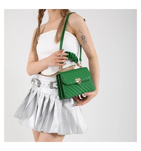 Detail of green quilted bag featuring heart-shaped metal lock and ruched handle