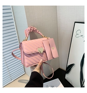 Pink quilted crossbody bag with heart lock, ruched handle, and small side coin pouch