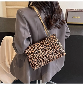 Detail of trendy leopard print tote bag with golden chain strap on a stylish woman