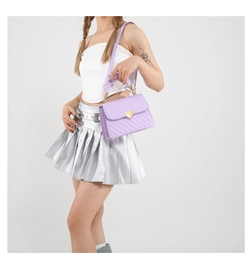 Model showing purple quilted crossbody bag with golden heart buckle and ruched handle detail