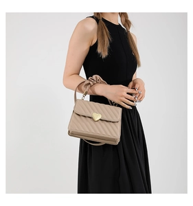 Detail of scrunchie handle and golden heart buckle on a beige quilted crossbody bag