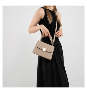 Detail of beige quilted small square bag featuring a gold heart-shaped metal lock