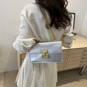 Modern metallic silver shoulder bag with gold geometric buckle and chain strap shown on model