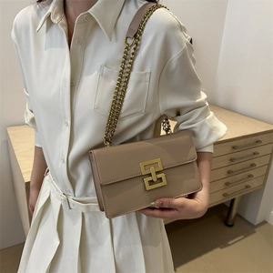 Minimalist beige crossbody bag with interlocking gold clasp and chain strap