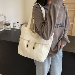 Minimalist off-white canvas tote bag with dual front zipper pockets for daily commute