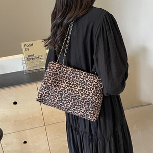 Leopard print tote bag with metal chain strap shown on model in a modern room setting