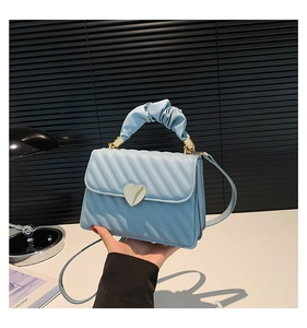 Light blue quilted handbag featuring a golden heart lock and ruched handle detail