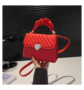 Detail of red crossbody bag with pleated texture and silver heart buckle closure