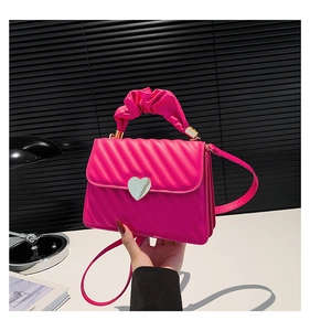 Detail of rose pink quilted crossbody bag with silver heart-shaped metal twist lock