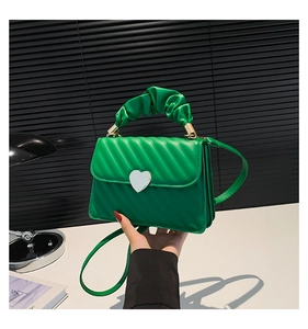 Detail of green faux leather bag with cloud pleated handle and heart-shaped metal buckle