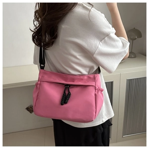 Close-up of pink crescent tote with black zipper and adjustable crossbody strap
