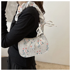 Detail of floral hobo bag featuring bow tie strap and pleated shoulder design