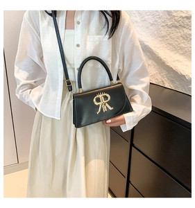 Detail of a chic black leather crossbody bag with a distinctive gold metal R logo