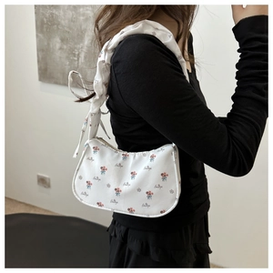 Detail of white canvas tote bag featuring floral prints and stylish bow knot on shoulder strap