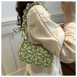 Floral hobo bag with daisy print and ruffled shoulder strap shown on a beige outfit