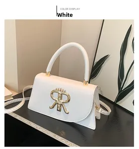 Detailed view of a white crossbody bag with gold metal RR logo on a dark display stand