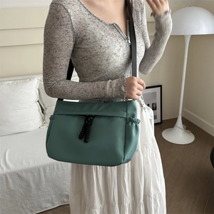 Fashionable dark teal nylon crossbody tote bag with adjustable strap and side pockets