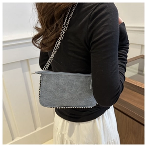 Detail view of gray denim bag featuring silver metal rivets and chain strap on shoulder
