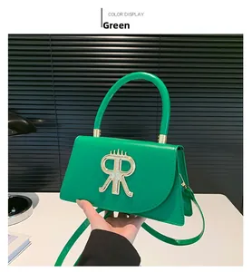 Close-up of green leather handbag featuring a distinct metallic R logo and curved handle