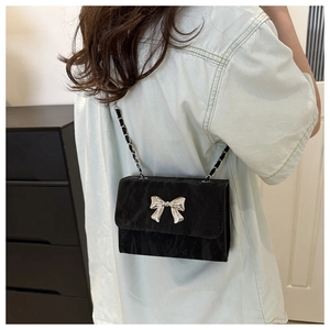 Close-up of black square chain bag with silver bow accent and textured fabric detail