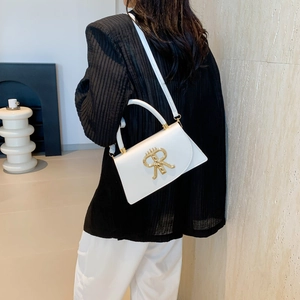 White leather handbag with a gold R-shaped clasp shown on a model for a chic look