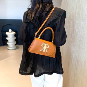 Fashion caramel leather crossbody bag with crown logo shown on a model in profile