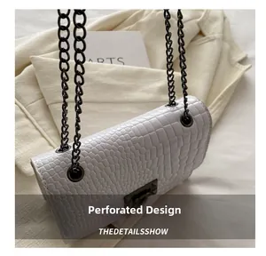Detail of white crocodile pattern shoulder bag with black chain and metal twist lock