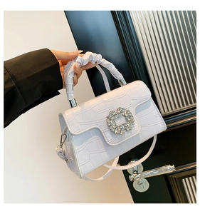 Detailed view of lavender crocodile-embossed bag with crystal buckle and pleated handle