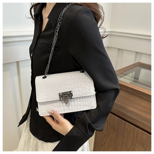 Detailed view of white crocodile pattern crossbody bag with dark grey metal chain strap