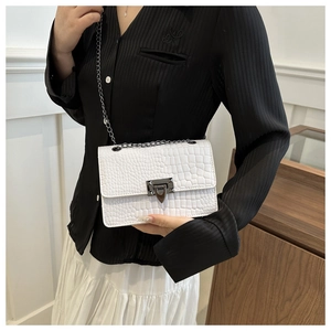Detail of white crocodile pattern square bag with metal chain strap and rectangle lock