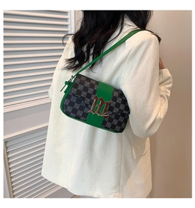 Dettaglio della borsa a spalla verde con patta a quadri e chiusura dorata elegante